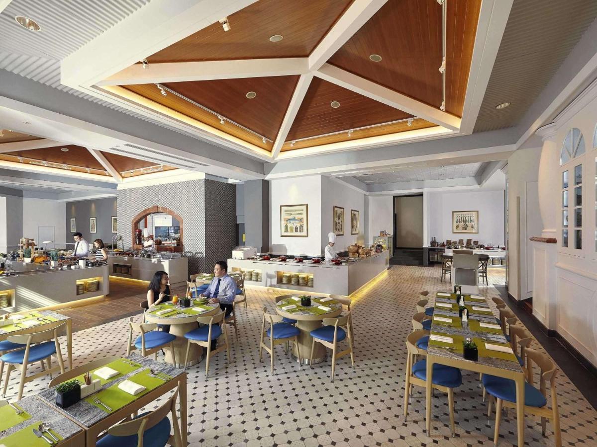 Paradox Singapore Merchant Court At Clarke Quay Экстерьер фото The photo depicts a modern restaurant interior. The space features a stylish design with a high ceiling and wooden details, creating an inviting atmosphere. 

Tables are neatly arranged, each set with green placemats and blue chairs. There is a secti