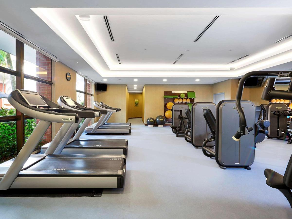 Paradox Singapore Merchant Court At Clarke Quay Экстерьер фото The photo shows a fitness gym interior that features several exercise machines and equipment. There are three treadmills positioned next to a large window, allowing natural light to enter the space. Alongside the treadmills, various types of strength