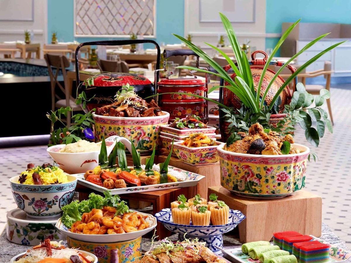 Paradox Singapore Merchant Court At Clarke Quay Экстерьер фото The photo displays a vibrant and lavish spread of various dishes arranged on a table. There are colorful bowls filled with different types of food, including rice, noodles, and an assortment of meats and vegetables. Some dishes are garnished with fre