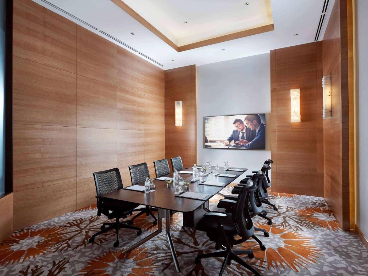 Paradox Singapore Merchant Court At Clarke Quay Экстерьер фото The photo shows a modern conference room. It features a large rectangular table surrounded by several black chairs. The walls are primarily made of wood, creating a warm, sophisticated atmosphere. A large screen is mounted on one wall, displaying a p