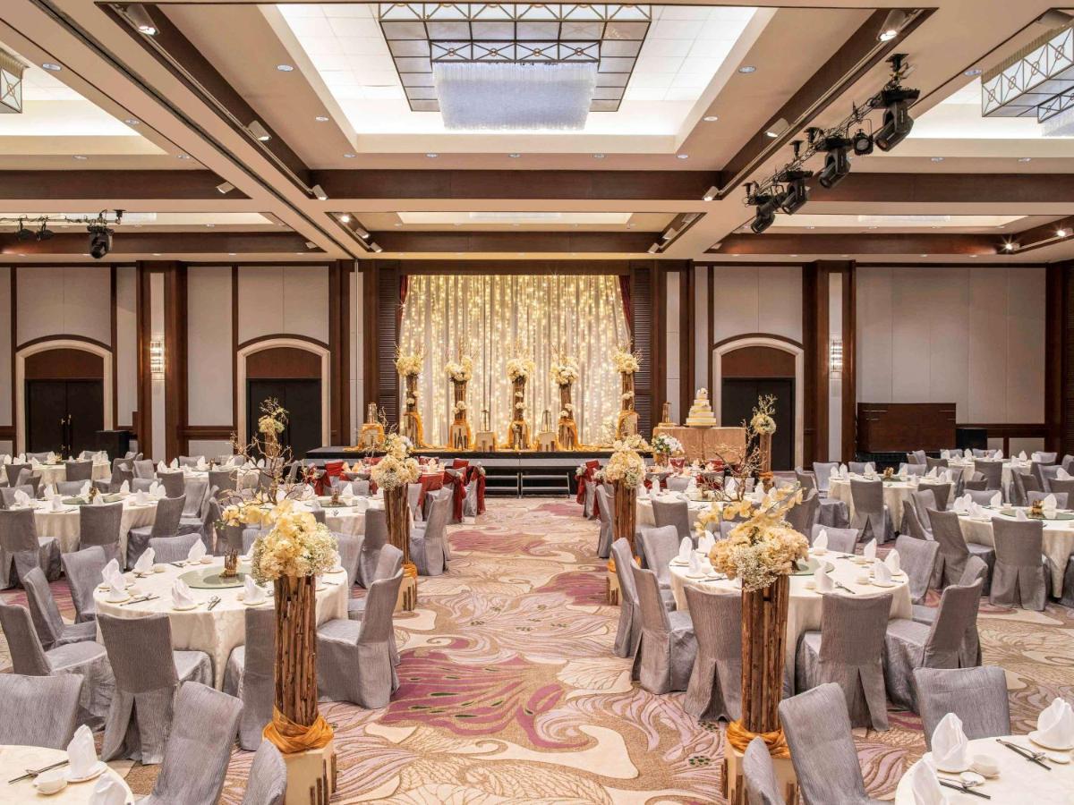 Paradox Singapore Merchant Court At Clarke Quay Экстерьер фото The photo depicts an elegant banquet hall set up for an event. The room features numerous round tables draped in white and gray tablecloths, each adorned with floral centerpieces. The chairs are covered in gray fabric with white accents. At the front