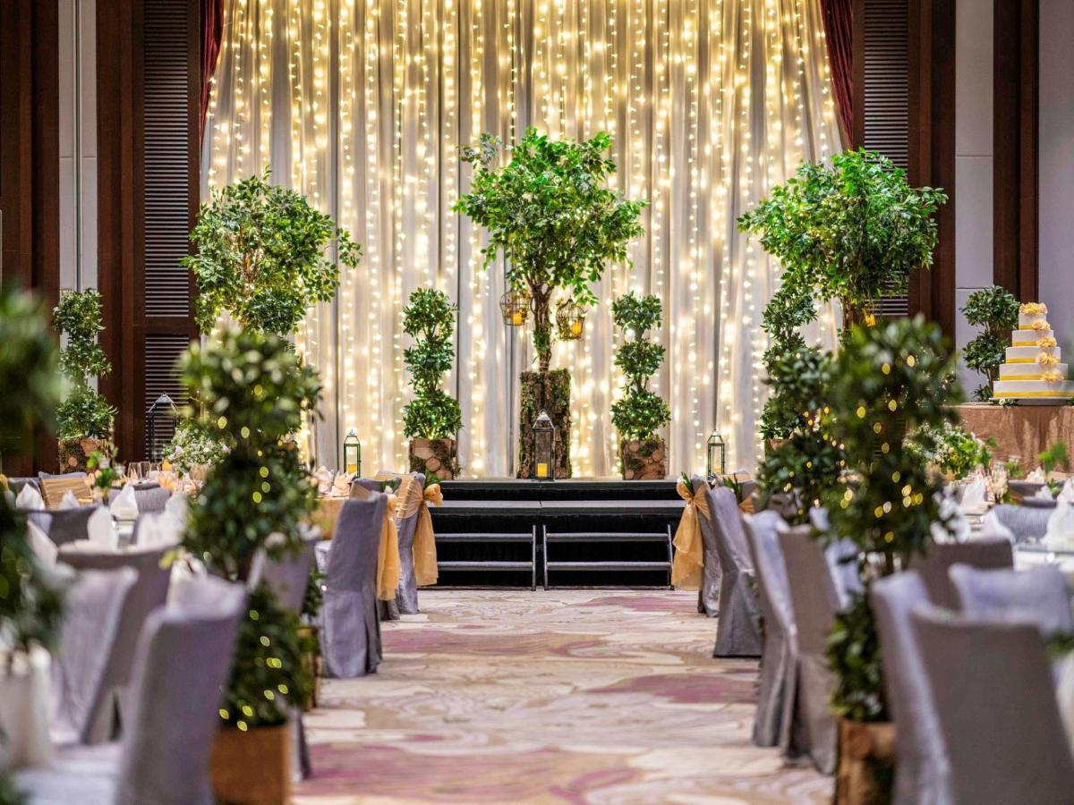 Paradox Singapore Merchant Court At Clarke Quay Экстерьер фото The photo shows a beautifully decorated event space, likely set up for a wedding or a formal gathering. The scene features:

- A backdrop of draped fabric embellished with twinkling fairy lights, creating a romantic ambiance.
- Several potted greener