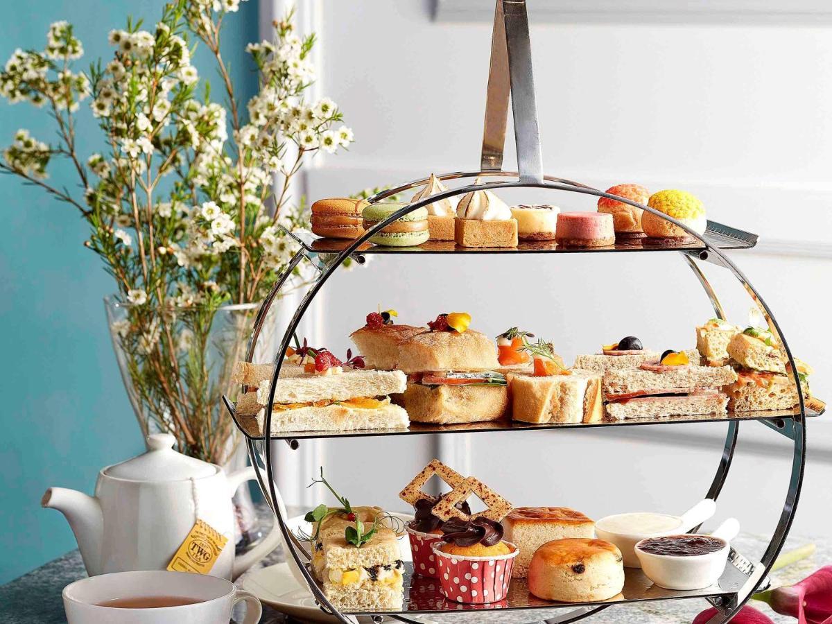 Paradox Singapore Merchant Court At Clarke Quay Экстерьер фото The photo features a tiered serving stand filled with an assortment of delightful treats. Each layer displays a variety of items, including sandwiches, pastries, and small cakes. The bottom tier showcases a selection of sweets, such as scones and col