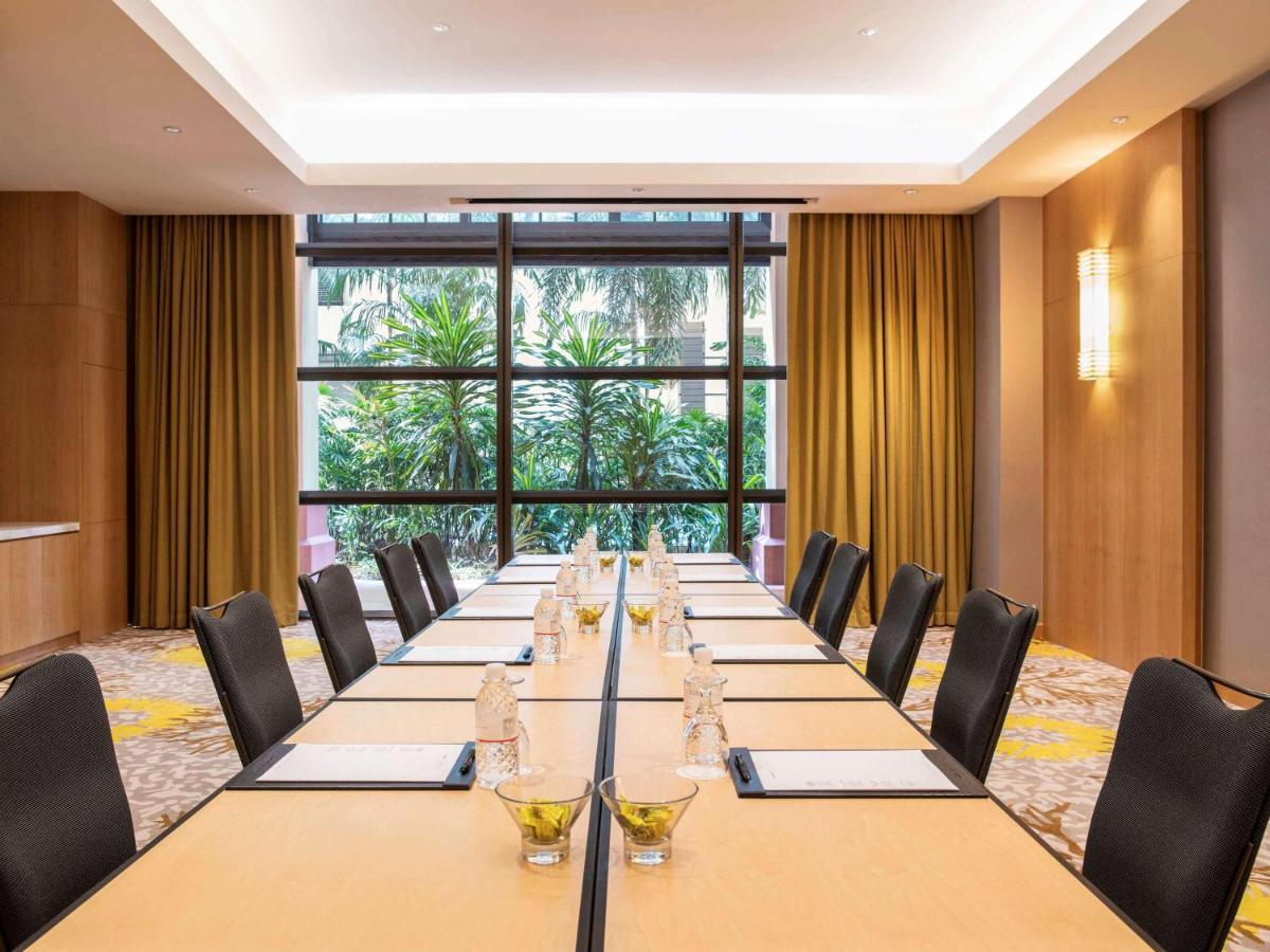 Paradox Singapore Merchant Court At Clarke Quay Экстерьер фото The photo shows a conference room set up for a meeting. There is a long rectangular table with chairs on both sides. Each place setting has a notepad, pen, and a small glass of water. The room features large windows with plants visible outside, along