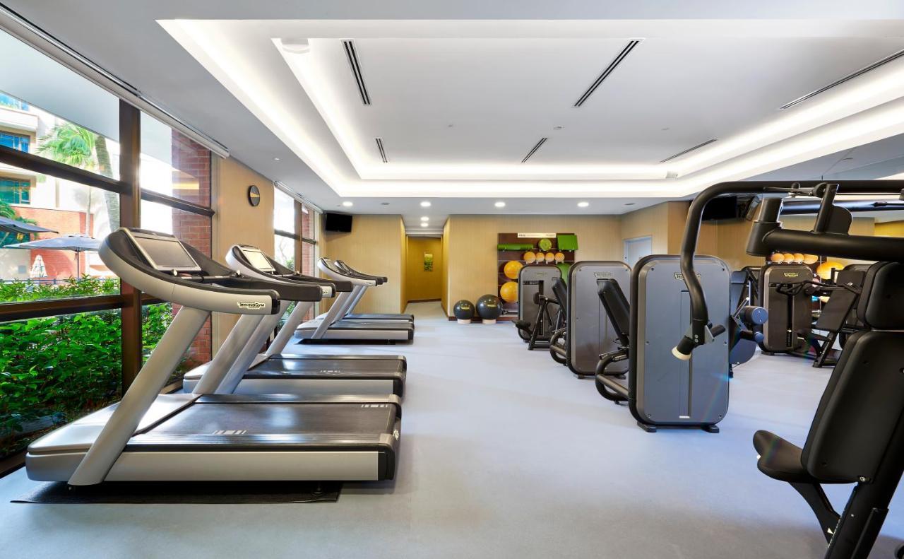 Paradox Singapore Merchant Court At Clarke Quay Экстерьер фото The photo depicts an indoor gym or fitness area. There are several modern treadmills lined up against one wall, with large windows allowing natural light to enter. The gym features various fitness machines arranged throughout the space, including str
