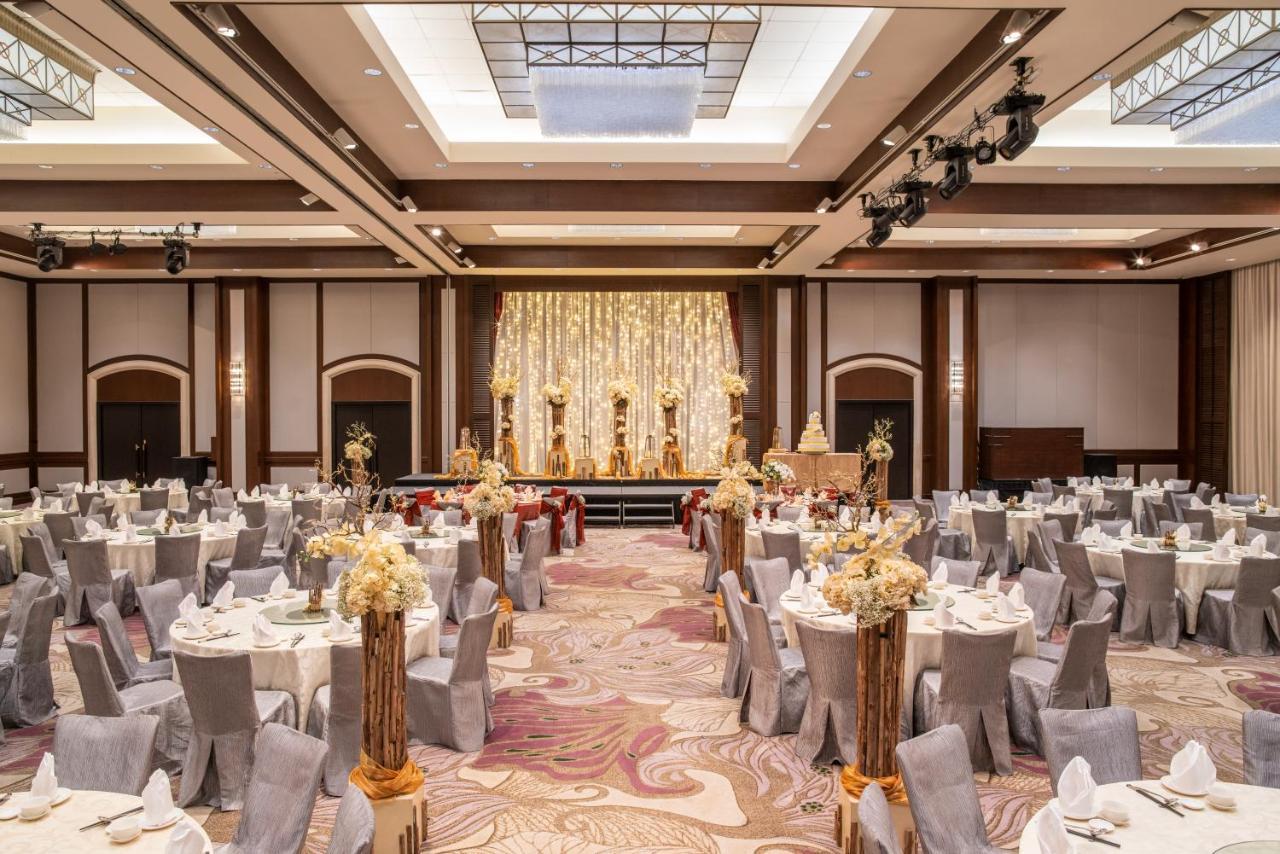 Paradox Singapore Merchant Court At Clarke Quay Экстерьер фото The photo shows an elegantly arranged banquet or event hall. There are several round tables covered with white tablecloths and decorated with floral centerpieces, creating a sophisticated atmosphere. The chairs are covered in grey fabric, complementi