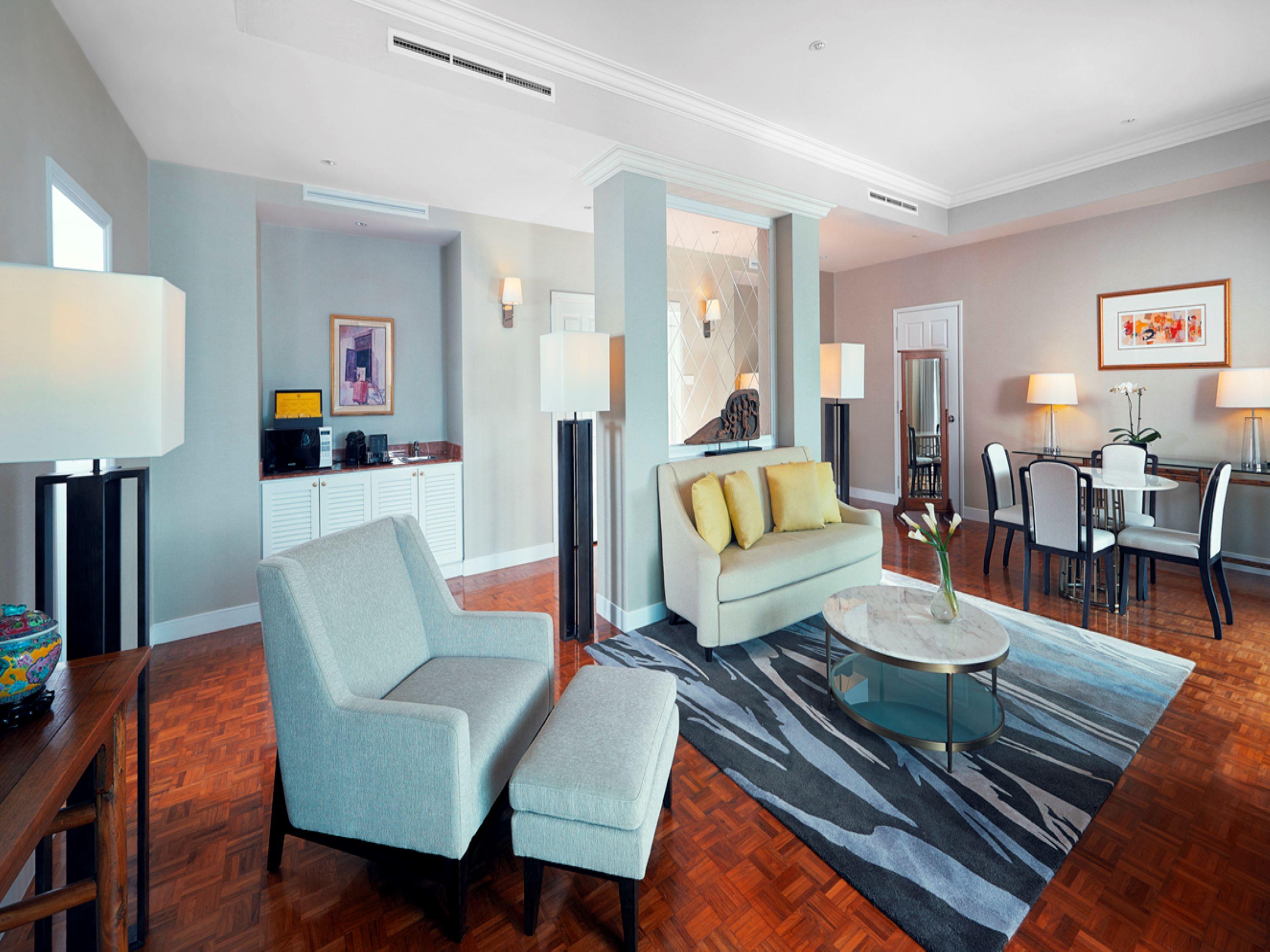 Paradox Singapore Merchant Court At Clarke Quay Экстерьер фото The photo shows a modern and stylish living space. It features a pair of light-colored armchairs and a settee with yellow cushions, arranged around a circular glass coffee table. A patterned area rug lies underneath. There are floor lamps providing l