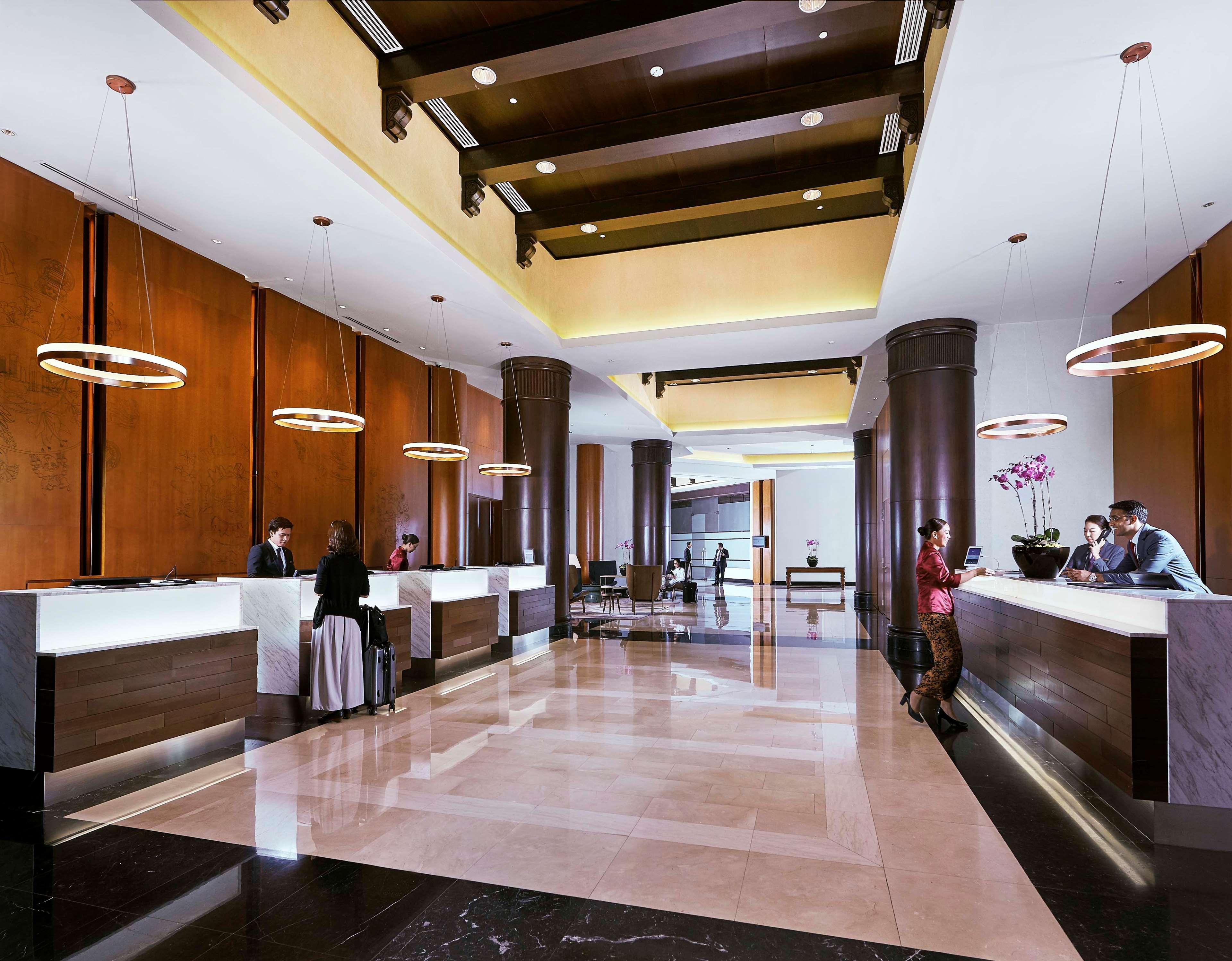 Paradox Singapore Merchant Court At Clarke Quay Экстерьер фото The photo depicts a hotel lobby with a modern and elegant design. It features a spacious area with high ceilings, stylish lighting fixtures, and large pillars. There are reception desks on either side, where staff members are attending to guests. The