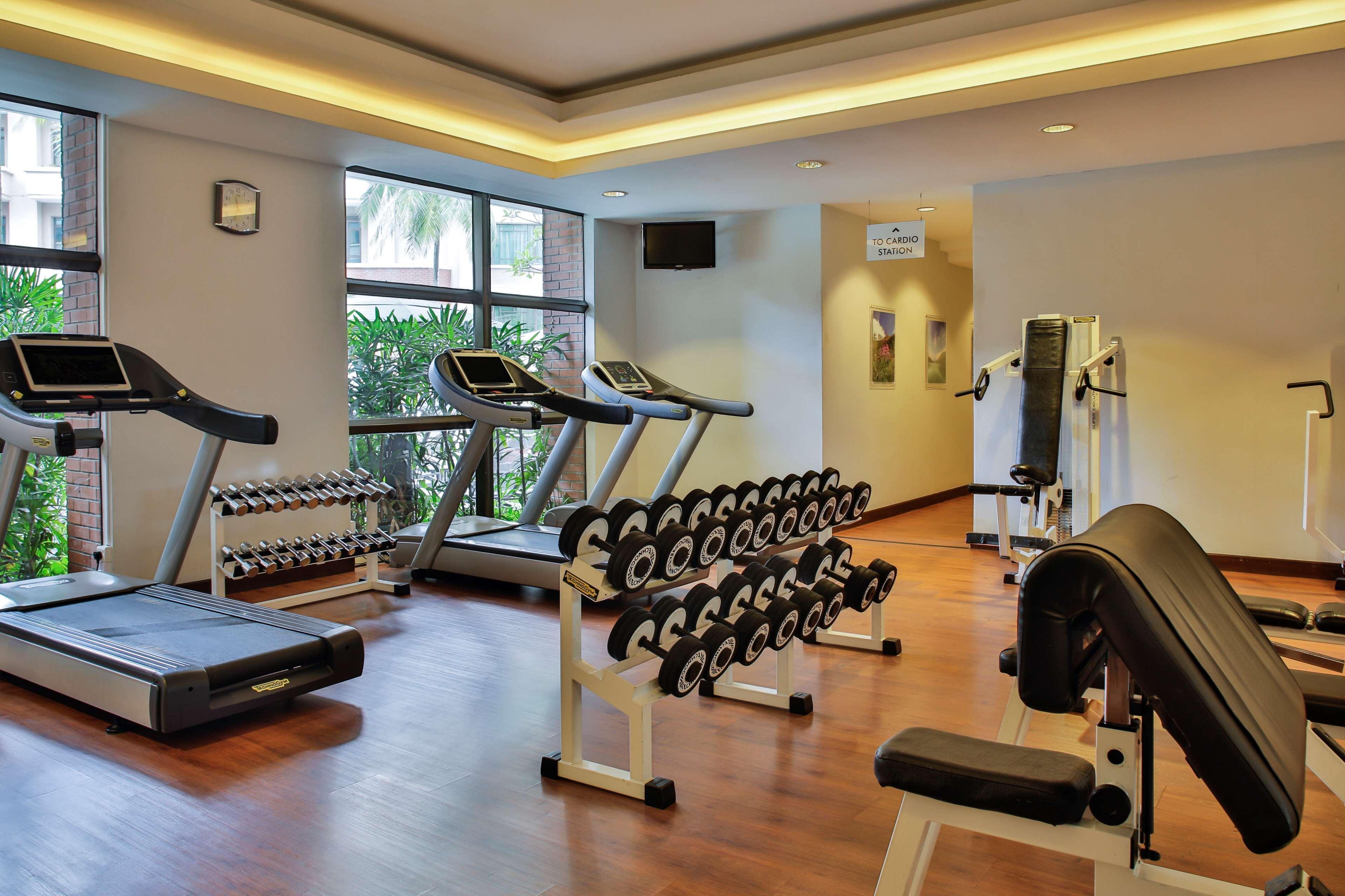 Paradox Singapore Merchant Court At Clarke Quay Экстерьер фото The photo shows a gym or fitness area featuring various exercise equipment. There are two treadmills positioned near a window, allowing natural light to brighten the space. A set of dumbbells is neatly organized on a rack, prominently displayed. Addi