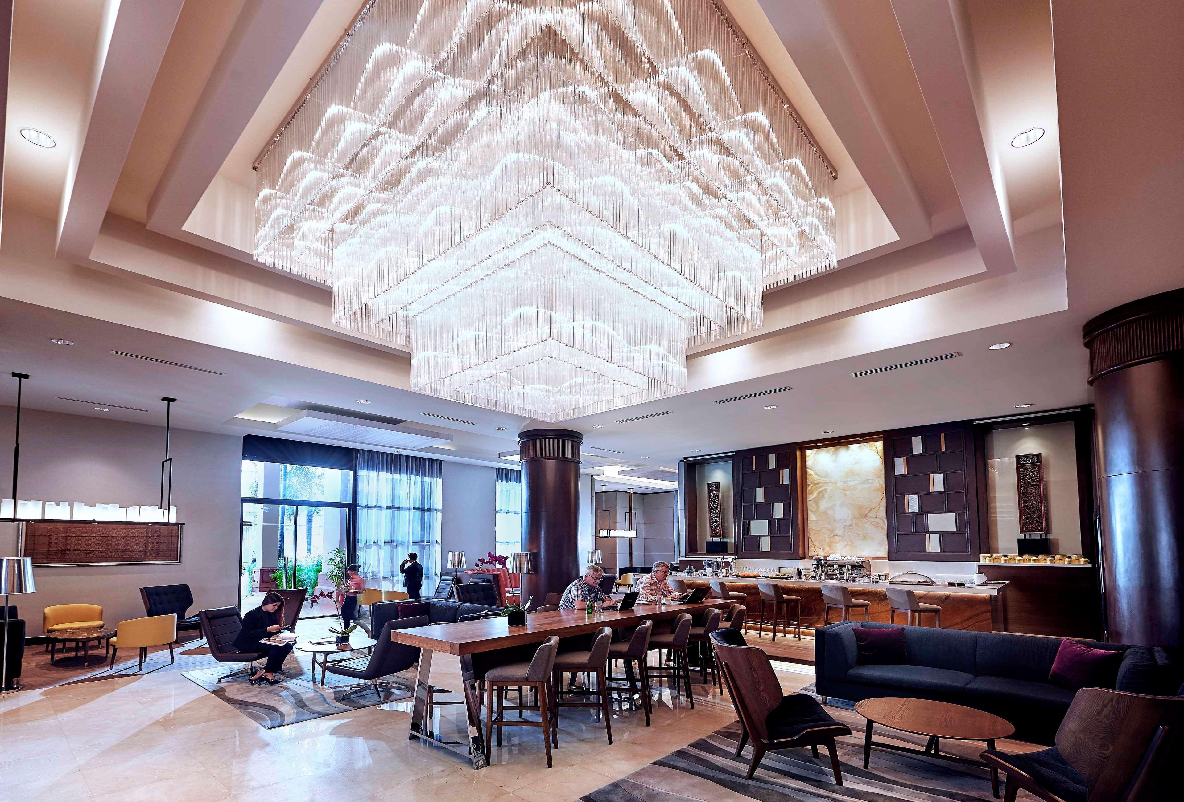Paradox Singapore Merchant Court At Clarke Quay Экстерьер фото The photo shows a modern and stylish interior space, likely a hotel lobby or lounge. A large, intricate chandelier hangs from the ceiling, illuminating the area with soft light. The floor is composed of elegant tiles, and there is a mix of seating ar