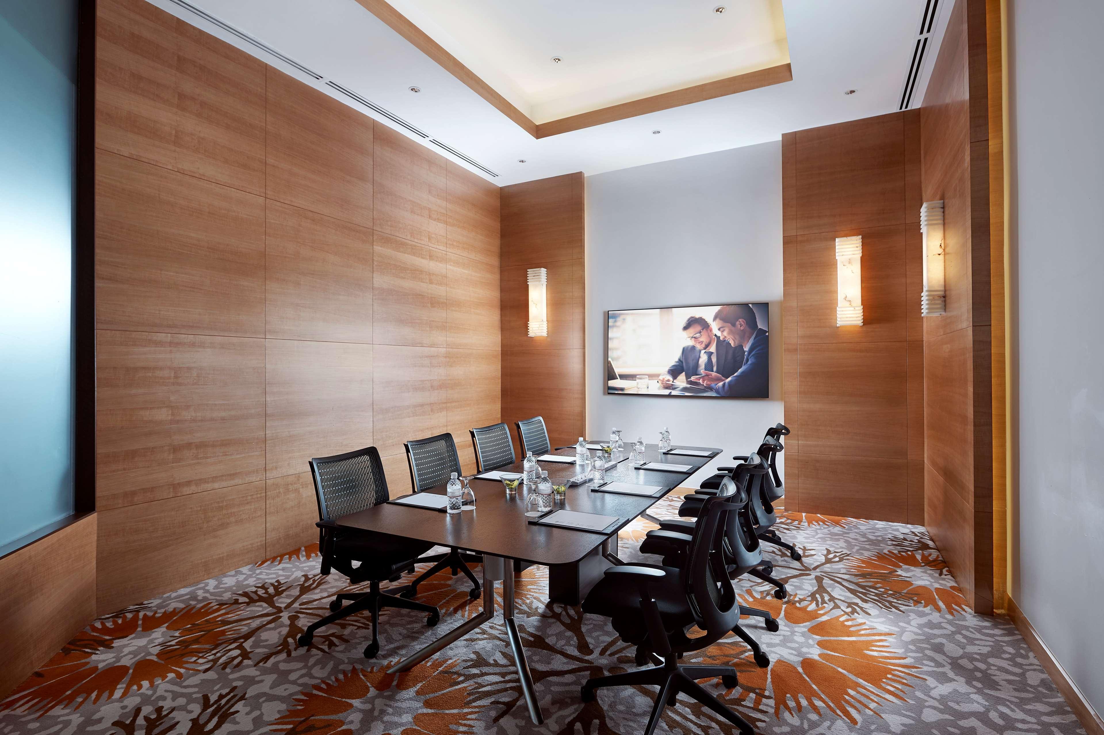 Paradox Singapore Merchant Court At Clarke Quay Экстерьер фото The photo shows a modern conference room featuring a large wooden table surrounded by several black office chairs. The room has wooden paneling on the walls, creating a warm ambiance. There's a large screen mounted on one wall, likely for presentatio