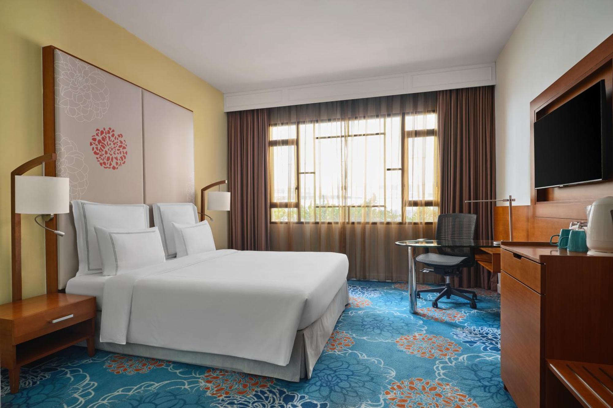 Paradox Singapore Merchant Court At Clarke Quay Экстерьер фото The photo shows a hotel room featuring a modern and inviting design. It includes a bed with white linens, two bedside lamps, and a decorative wall behind the bed. There is a large window covered with sheer and dark curtains, allowing natural light to
