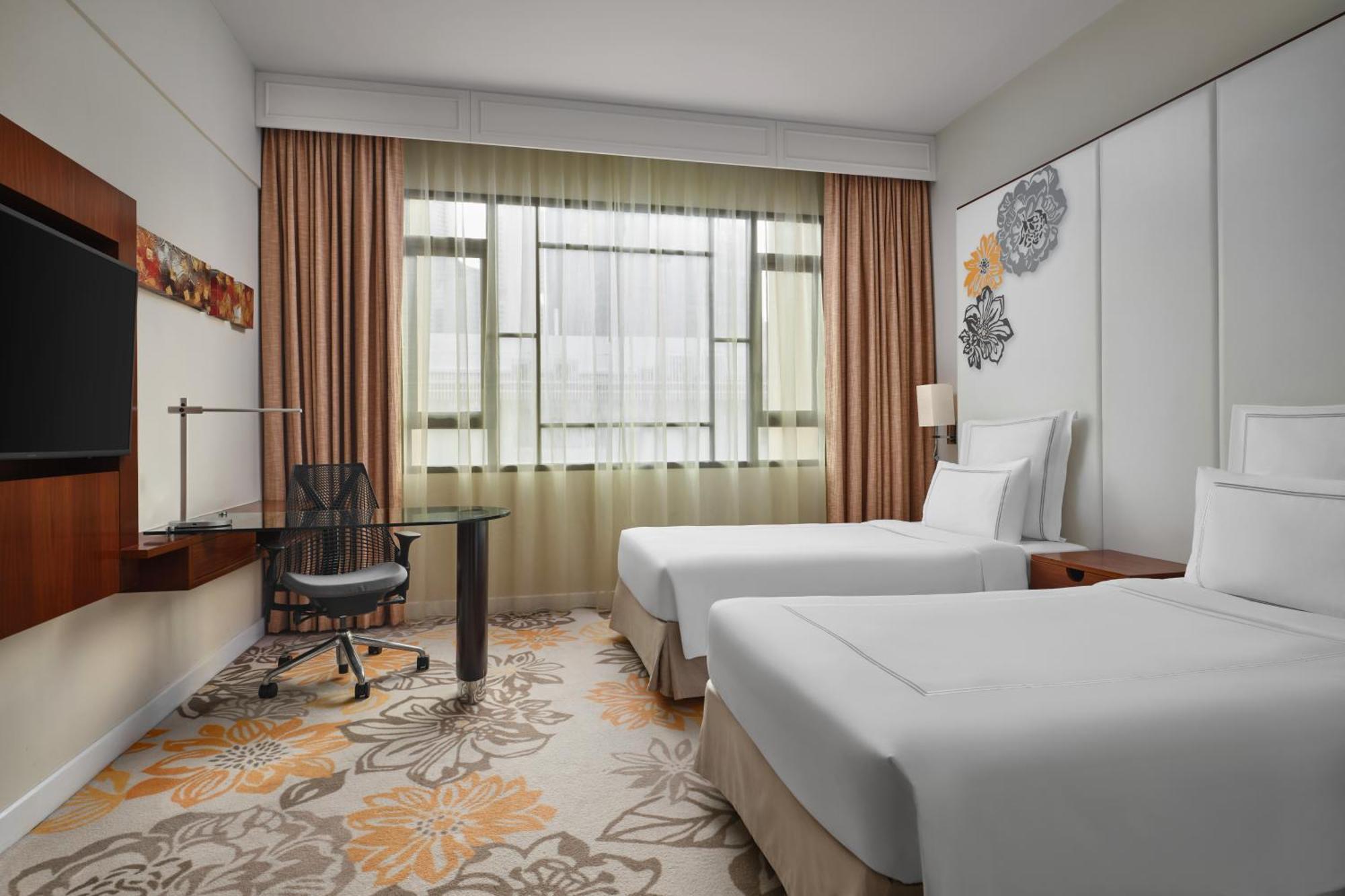 Paradox Singapore Merchant Court At Clarke Quay Экстерьер фото The photo shows a modern hotel room featuring two twin beds with white bedding. There is a large window with sheer curtains allowing natural light to fill the space. In the corner, there's a stylish desk with an ergonomic chair. The room has a light 